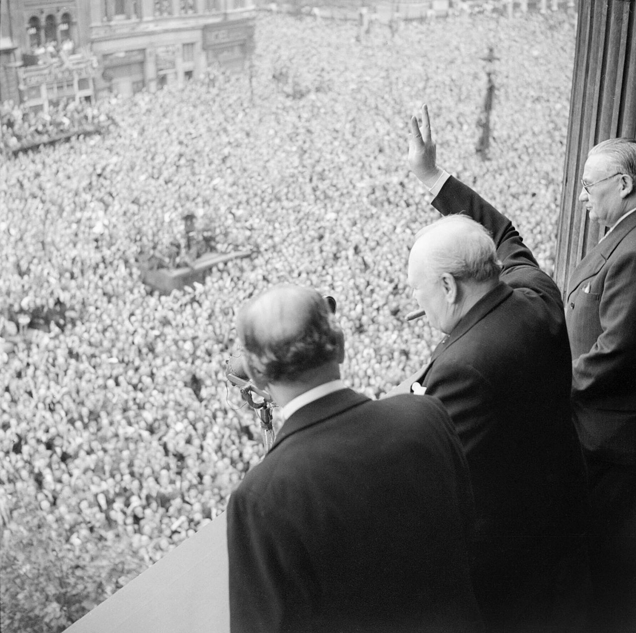 1280px-Winston_Churchill_waves_to_crowds_in_Whitehall_in_London_as_they_celebrate_VE_Day,_8_May_1945._H41849.jpg